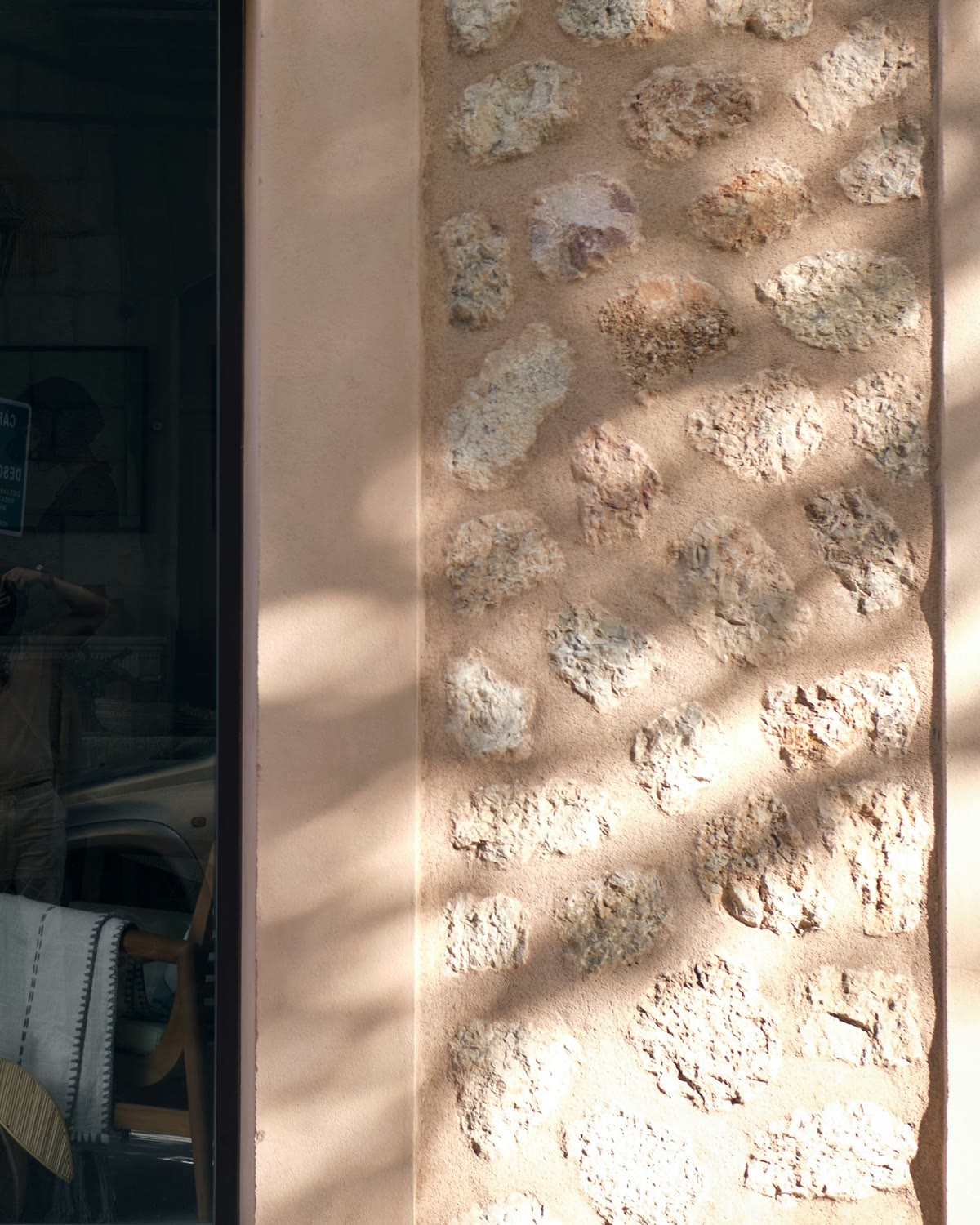 Concept store frontage in warm stone with a single lit vitrine at dusk